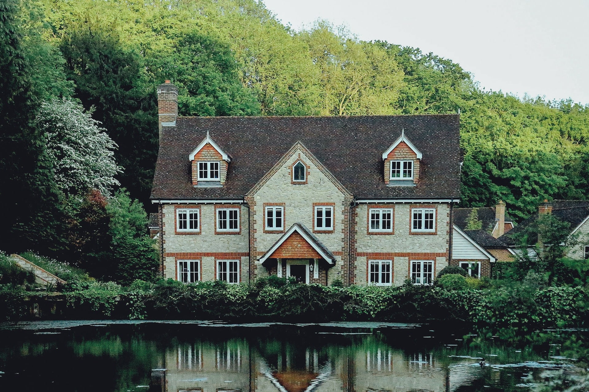 Grande maison un peu ancienne mais en très bon état qui semble être située dans les montagnes. Elle borde un lac, au milieu de l'a verdure et des forêts.