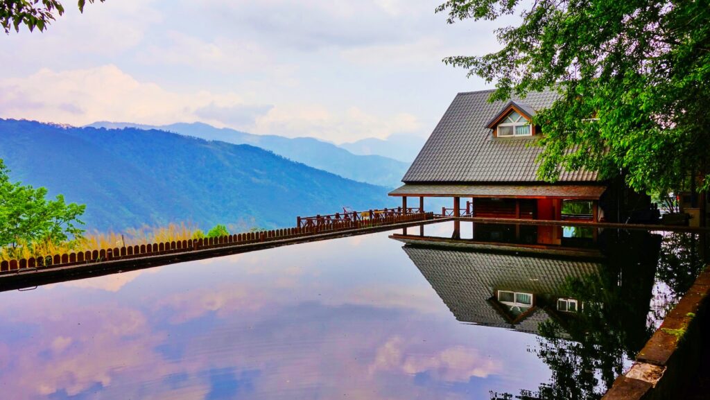 Maison qui surplombe une vue montagneuse et panoramique avec une piscine gigantesque et luxueuse qui reflète un ciel profond et bleu.