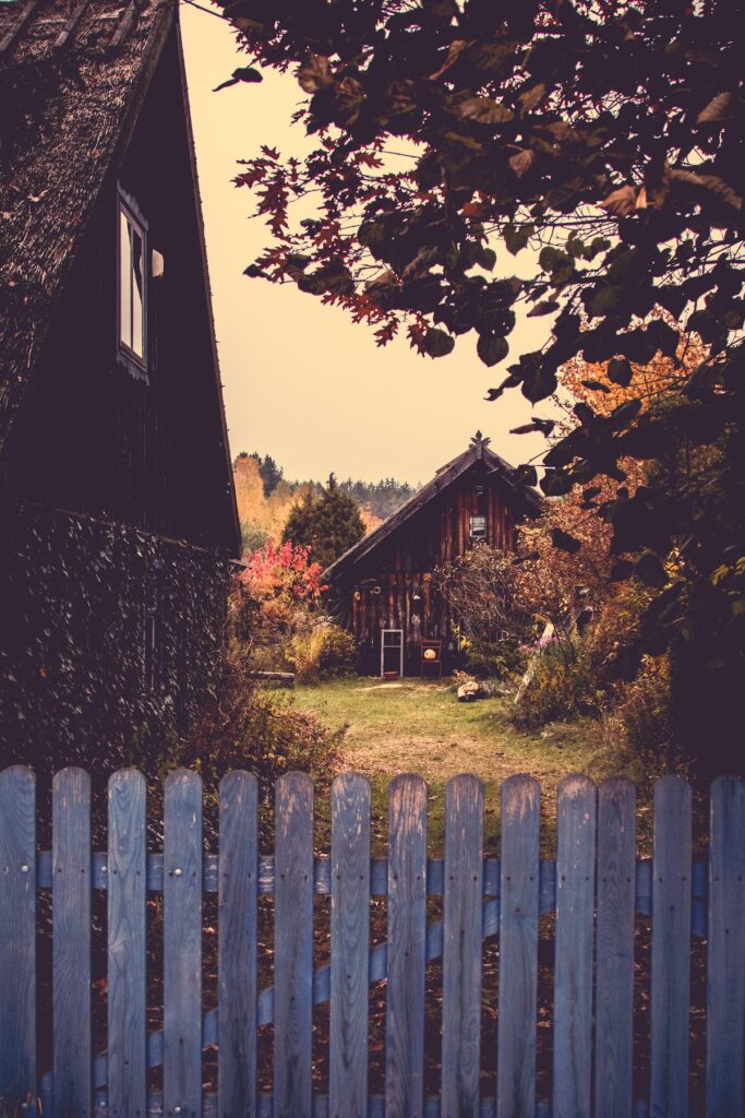 l'image montre une barrière en bois qui délimité le terrain d'une maison dans un coin paisible à la campagne.