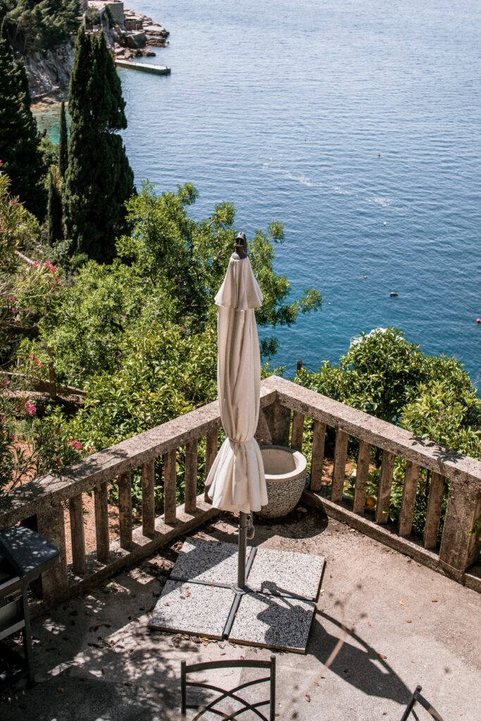 Parasol fermé sur terrasse en pierre avec vue sur mer.