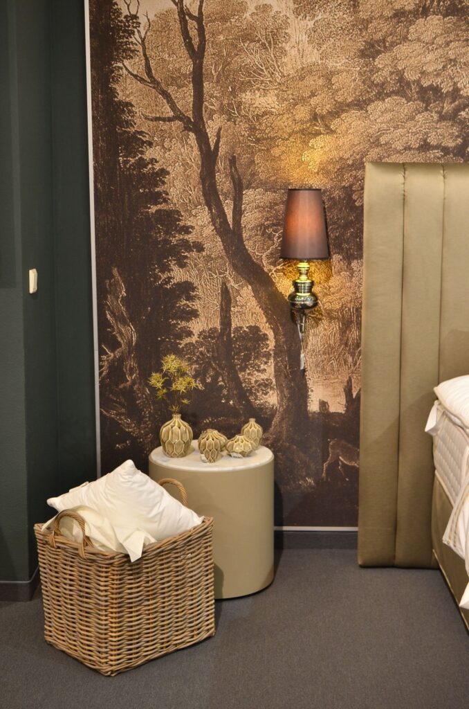 vue sur le mur d'une chambre contre le lit, dont le motif représente un paysage avec des silhouettes végétales