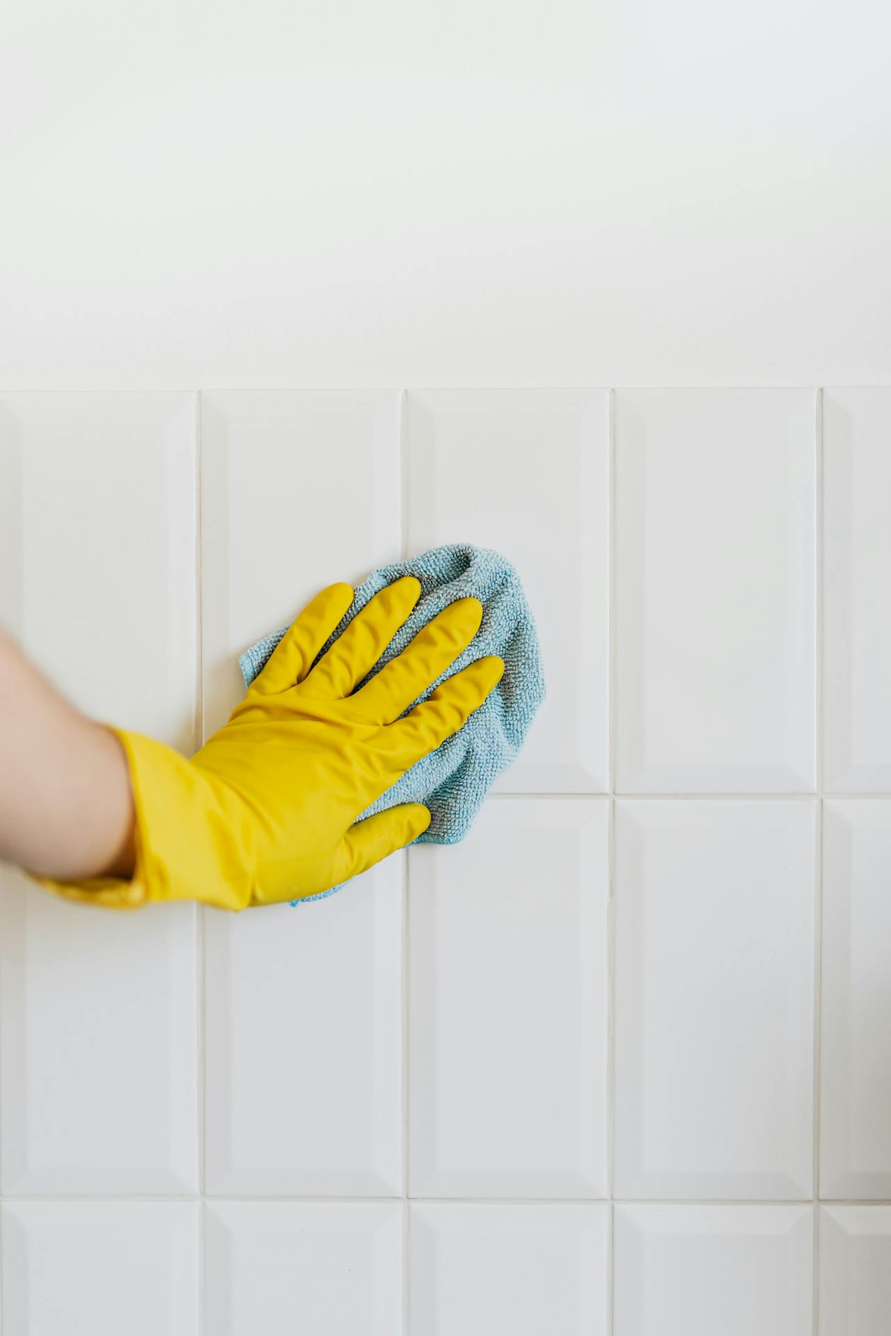 personne qui nettoie un mur ( gant jaunes et chiffon)