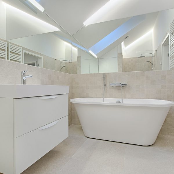 Salle de bain carrée complètement blanche. Les murs, sol & meubles sont blanc.